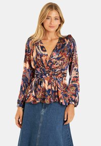 Blusa a stampa floreale con scollatura a V profonda, maniche lunghe con polsini e vita cintrata, realizzata in tessuto leggero nei toni di blu, rosa e verde.