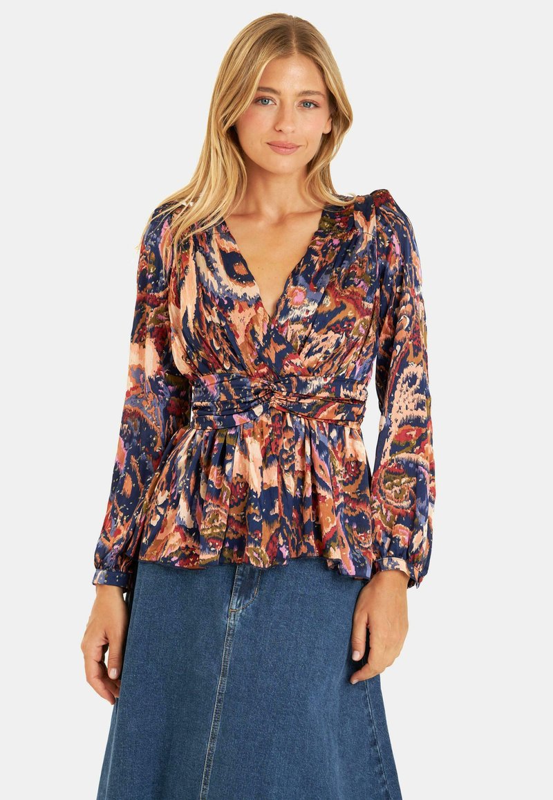 Blusa a stampa floreale con scollatura a V profonda, maniche lunghe con polsini e vita cintrata, realizzata in tessuto leggero nei toni di blu, rosa e verde.