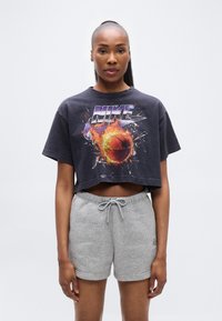 Μαύρο κοντομάνικο μπλουζάκι με πολύχρωμη γραφική εικόνα μπάσκετ και το κείμενο "NIKE", συνοδευόμενο από γκρι σορτς φόρμας με ελαστική μέση.