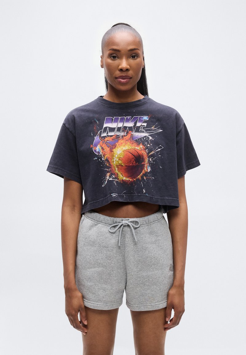 Μαύρο κοντομάνικο μπλουζάκι με πολύχρωμη γραφική εικόνα μπάσκετ και το κείμενο "NIKE", συνοδευόμενο από γκρι σορτς φόρμας με ελαστική μέση.