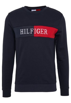 Mørkeblå crewneck sweatshirt med lange ærmer, med et rødt og mørkeblåt rektangulært panel og hvid "HILFIGER" tekst henover brystet.