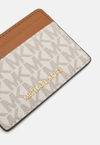 Portafoglio realizzato in materiale sintetico beige con dettagli in pelle marrone, caratterizzato da un motivo geometrico e con logo dorato.
