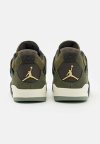 Sneakers in pelle scamosciata verde e pelle nera con un logo dorato, caratterizzate da un design del tallone prominente e una superficie testurizzata.