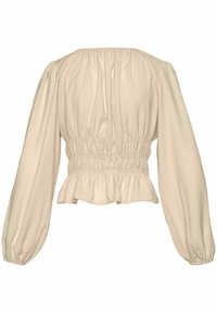 Ljus beige blus med samlad halsringning och smockad midja. Långa, luftiga ärmar med volangkant, gjord av mjukt tyg.