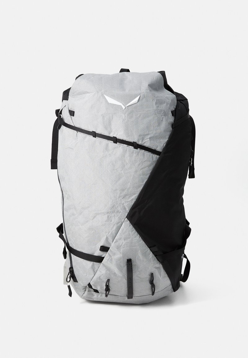 Gray and black patterned backpack with a triangular design, adjustable straps, top handle, and front zip pocket for accessories.