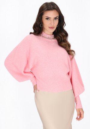 Pull en rose, surdimensionné, avec une finition texturée et de longues manches ballon. Présente des ornements décoratifs autour du cou.