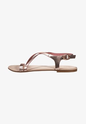 Sandalia plana en oro rosa con finas tiras, hebilla en el tobillo y diseño de punta abierta.