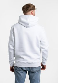 Sudadera blanca con capucha, de textura suave, con dobladillo y puños acanalados, y un bolsillo tipo canguro. La vista trasera muestra la capucha y un diseño limpio.