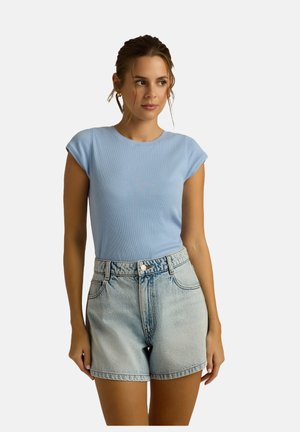 Jasnoniebieska, prążkowana koszulka z krótkim rękawem, w zestawie z wypłowiałymi szortami dżinsowymi na wysokim stanie z szlufkami na pasek.