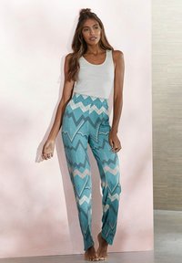 Turquoise patterned pants with zigzag designs in white and pink, paired with a fitted white tank top. The fabric appears lightweight.