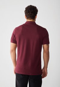 Bordeaux polo skjorte med korte ermer og klassisk krage, laget av myk tekstil, med en jevn overflate og en avslappet passform.