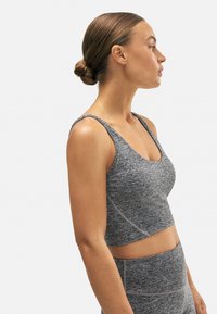 Top corto atlético gris hecho de material texturizado, con tirantes finos y escote redondeado. Tiene detalles de costura contrastantes.