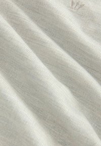 Țesătură de culoare gri deschis, cu o textură subtilă și un model diagonal. Prezintă un mic logo brodat într-o nuanță contrastantă. Moale și ușor șifonat.