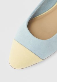 Μπλε σουέτ φλατ με μυτερή μύτη και κίτρινη σουέτ λεπτομέρεια στην άκρη, με  λεία εσωτερική επένδυση και σόλα σε φυσικό χρώμα.