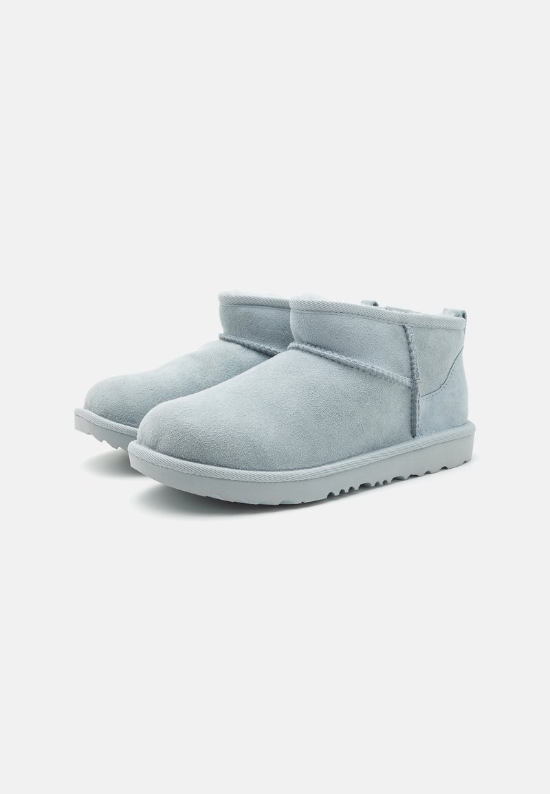 Bottines en suede bleu clair avec un bout arrondi, des accents cousus et une semelle en caoutchouc texturée. Design minimaliste avec un revers replié.