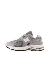 Chaussure de sport grise en matière maillée et suédée, avec une bande Velcro, une semelle en caoutchouc et un logo "N" sur le côté. Numéro de modèle 2002R.