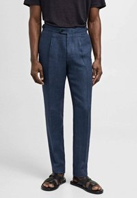Pantaloni su misura blu scuro con gamba dritta. Presentano una frontale piatta, doppi pieghe e chiusura con bottone. Abbinate a sandali neri.