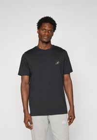 Sort bomulds T-shirt med korte ærmer og rund udskæring; har et lille logo på brystet; glat tekstur og afslappet pasform.