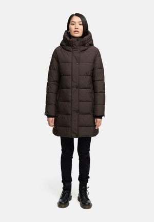 Manteau matelassé marron foncé avec un col haut, un devant à boutons, des poches zippées et une capuche. Associé à un pantalon noir et des bottes à lacets.