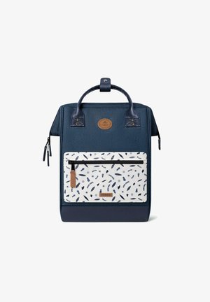 Sac à dos bleu marine en tissu texturé, avec une poche blanche ornée de motifs nautiques bleus et des accents en cuir. Anses supérieures et fermetures éclair.