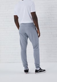 Grå joggerbyxor med elastisk midja och sidofickor, i kombination med en vit t-shirt och svarta sneakers. Strukturerad tyg med ribbad mudd.