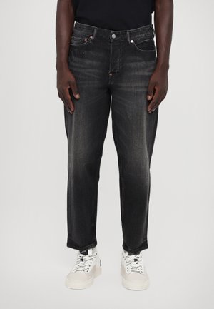 Black denim jeans with a slightly faded finish, featuring five pockets, silver hardware, and a straight-leg cut. Worn with white sneakers.