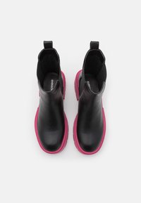 Mustat nahkakengät nilkkapituiset vaaleanpunaisilla kumipohjilla, joissa on sileä pinta ja joustavat sivupaneelit helppoa pukemista varten.