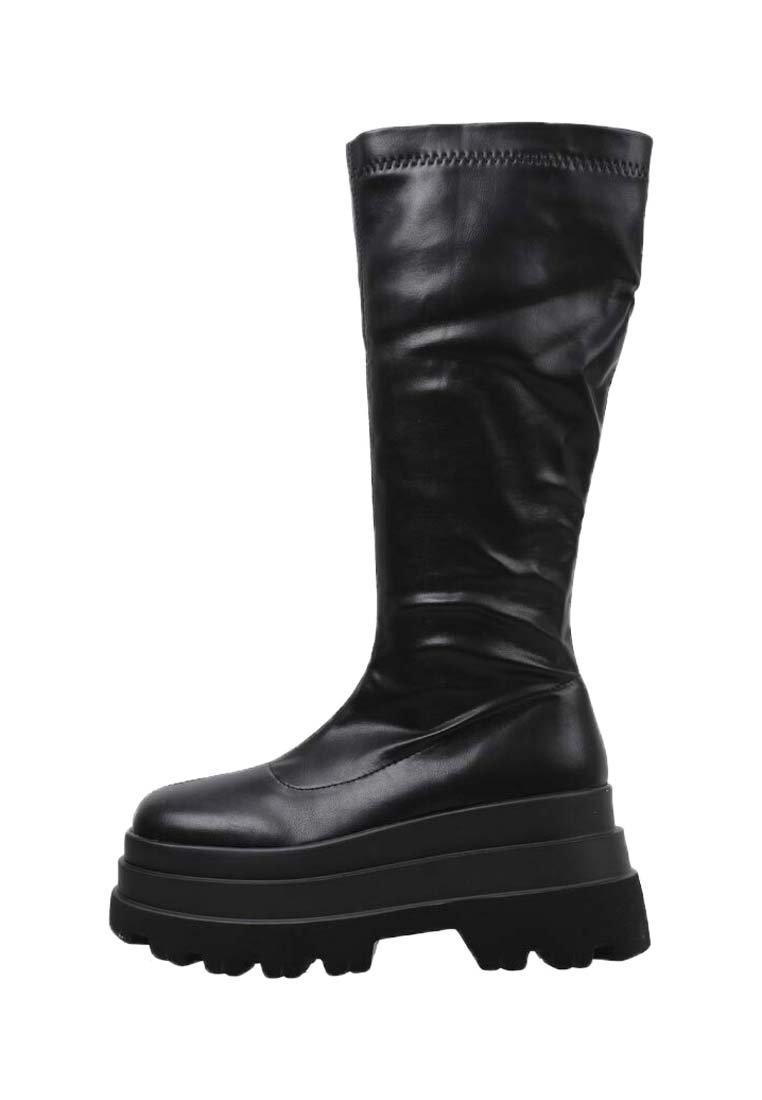 Botas altas negras de cuero suave con una suela gruesa de plataforma y un diseño texturizado en la parte superior. Presentan una puntera redondeada y detalles de costura.