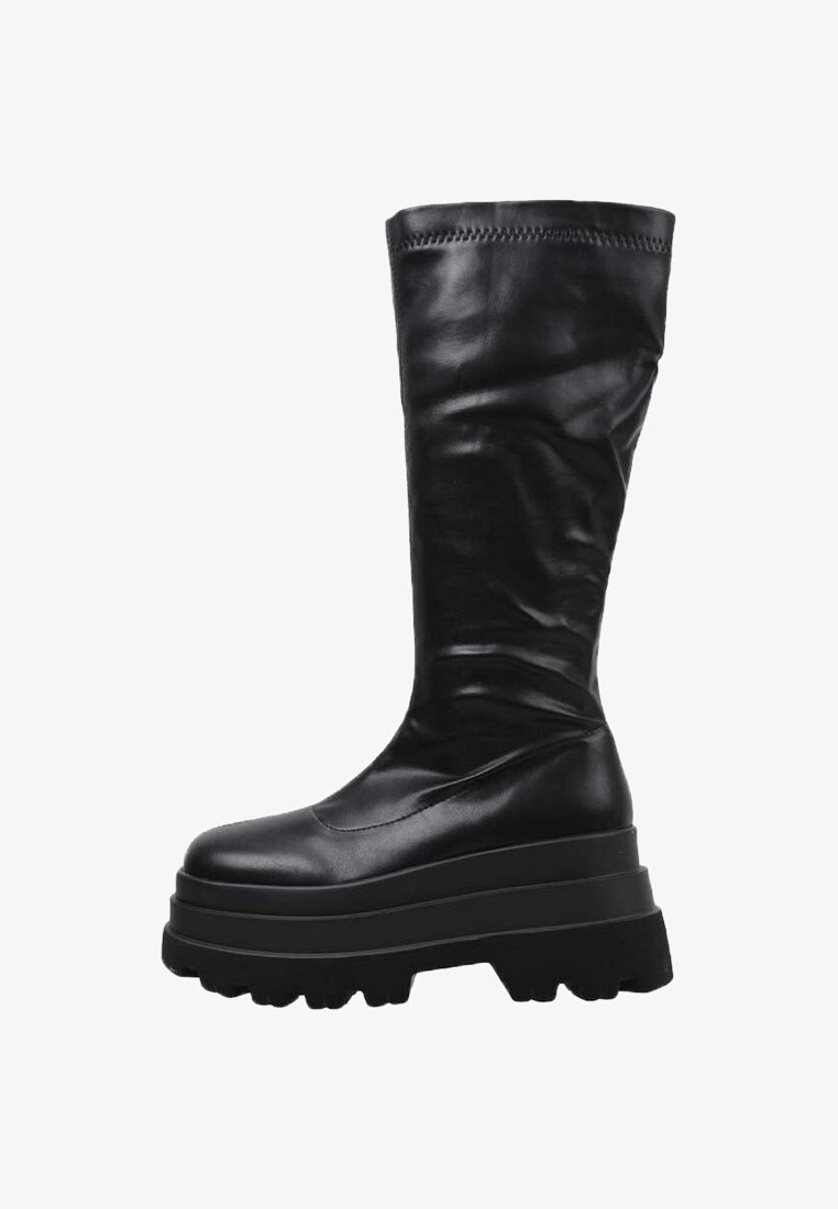 Botas altas negras de cuero suave con una suela gruesa de plataforma y un diseño texturizado en la parte superior. Presentan una puntera redondeada y detalles de costura.