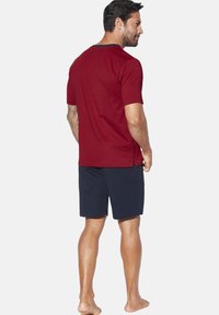 Red cotton t-shirt with short sleeves, featuring a navy collar trim, paired with navy shorts, both designed for comfort and casual wear.