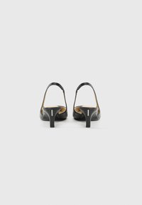 Sandali con tacco in pelle nera, dal design slingback e tacco sottile. Presentano una suola interna testurizzata e una silhouette minimali e moderna.
