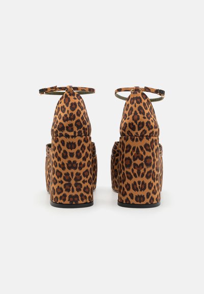 Een paar hoge sandalen met enkelbandjes en stevige vierkante hakken, bedekt met een bruin en zwart luipaardprintpatroon.