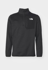 Sudadera de forro polar negra con media cremallera y cuello alto, que cuenta con un bolsillo en el pecho, un detalle de logo y una textura suave.