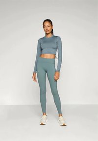 Világos türkiz színű, hosszú ujjú cropped top és a hozzá illő, magas derekú leggings, sima, rugalmas anyagból készült, és formázott kialakítással rendelkezik.