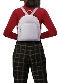 Ljust grå läderryggsäck med en slät yta. Har justerbara remmar, ett handtag på toppen och en framficka med dragkedja.