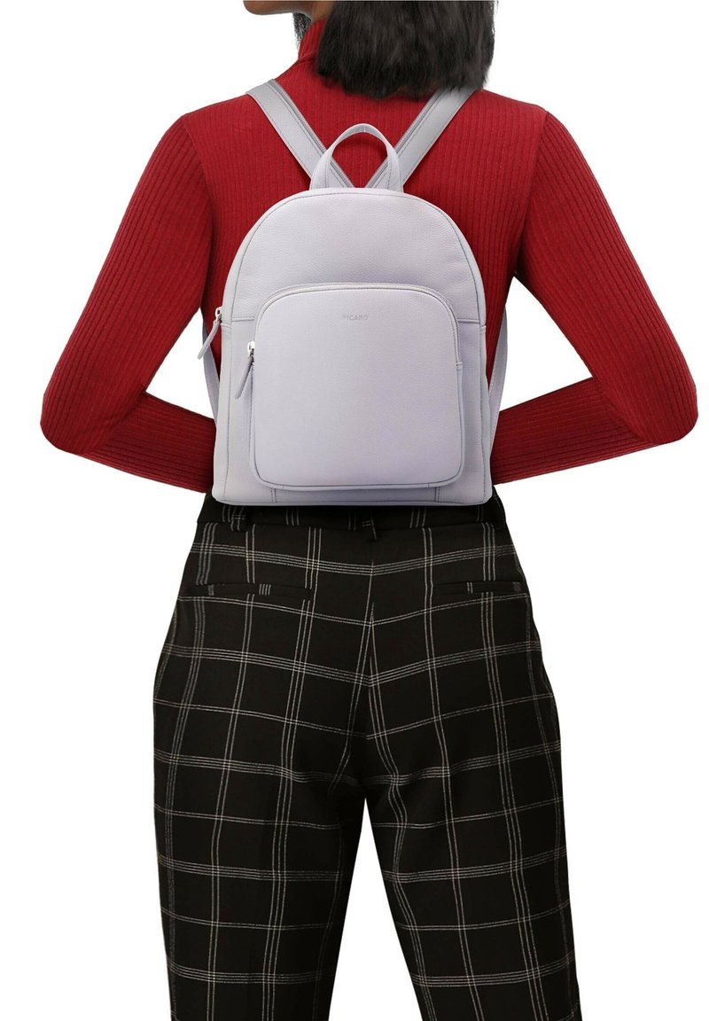 Ljust grå läderryggsäck med en slät yta. Har justerbara remmar, ett handtag på toppen och en framficka med dragkedja.