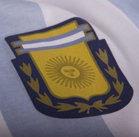 Geel en blauw schild met een zonembleem, omringd door laurierbladeren, op een lichtblauwe en witte gestreepte achtergrond.