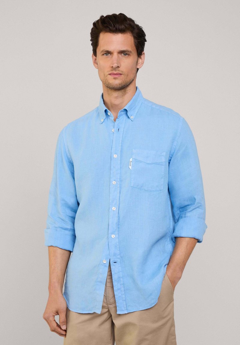 Camicia button-up azzurra in tessuto di lino con maniche lunghe arrotolate, dotata di taschino sul petto e bottoni bianchi.