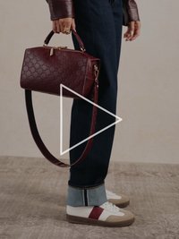 Bordoopunane nahast käekott reljeefse mustriga, pealuu käepide ja eemaldatav õlarihm. Tumedad teksad mansettidega ja valged tennised.