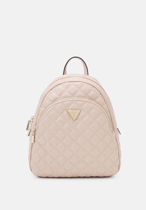 Petit sac à dos beige matelassé avec une poche avant zippée et un emblème de logo triangulaire doré sur un fond uni.