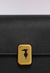 Černá kožená peněženka s texturou, která má zlatou obdélníkovou sponu s designem siluety zvířete. Hladký a embosovaný povrch.