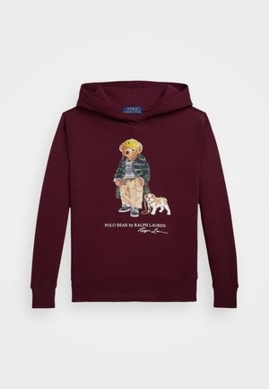 Sudadera color marrón con capucha que presenta un oso impreso con abrigo y sombrero, acompañado de un perro. Tiene un bolsillo en forma de canguro y puños acanalados.