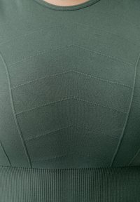 Zelený pletený top s okrúhlym výstrihom, s textúrovaným vzorom v tvare šípu a rebrovanými detailmi na spodnom leme. Mäkka tkanina.