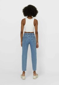 Ljusblå högmidjade jeans med avslappnad passform, femfickorsdesign och en kort vit linne. Slät tygtextur, minimal hårdvara.