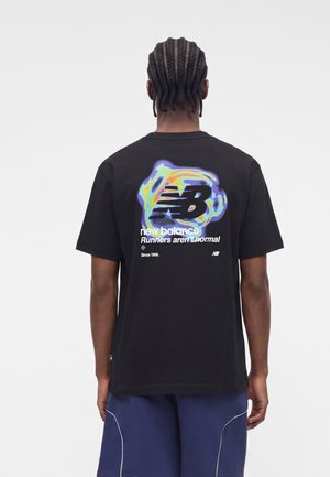 Homme aux cheveux tressés portant un t-shirt noir New Balance avec un logo coloré et le texte "Runners aren't normal" au dos, et un short bleu.