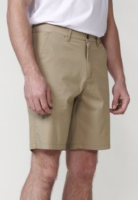 Shorts khaki dintr-un material ușor, cu închidere prin buton și fermoar, buzunare laterale și un design drept.