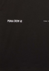 T-shirt en coton noir avec le texte blanc "PUMA CREW 48" et "PUMA TEE" en police sans-serif moderne. Sans motifs ni ornements.