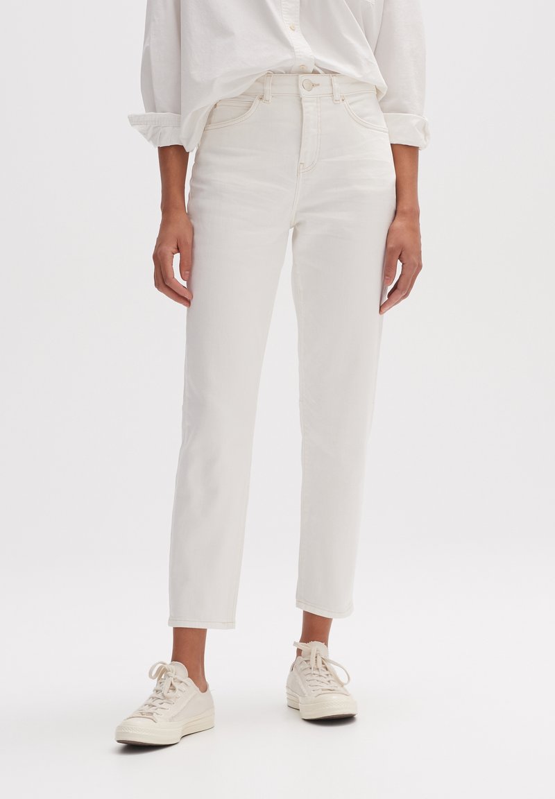 Vita jeans i denim med hög midja, raka ben och minimalistisk design, kombinerade med sneakers i krämfärg.