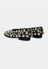 Bailarinas negras con puntera redondeada, adornadas con tachuelas metálicas en dorado y plateado, que aportan un diseño texturizado y visualmente impactante.