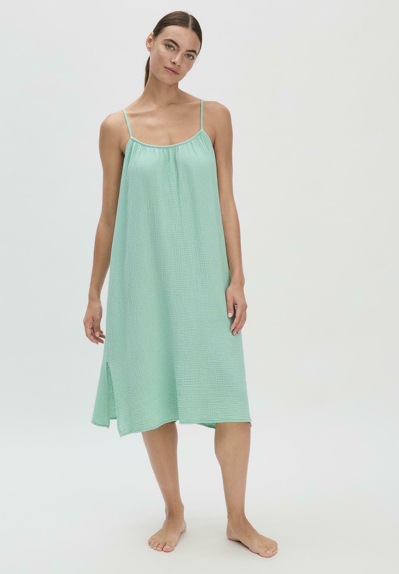 Hellgrünes, ärmelloses Kleid mit entspannter Passform, strukturiertem Stoff und kleinem Seitenschlitz für Bewegungsfreiheit. Weiches, atmungsaktives Material.